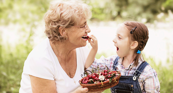 Abuela y nieta comiendo fruta.