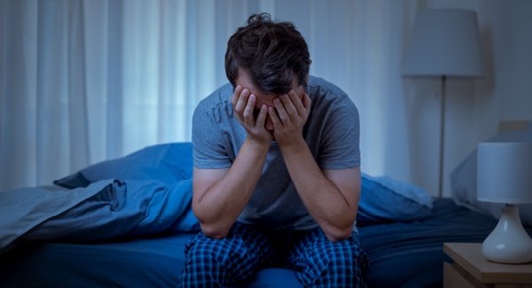 Man with head in hands on bed