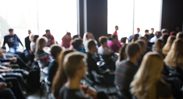 foto borrosa de grupo grande de personas sentadas en una sala de conferencias