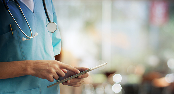 Body of doctor looking at a tablet.