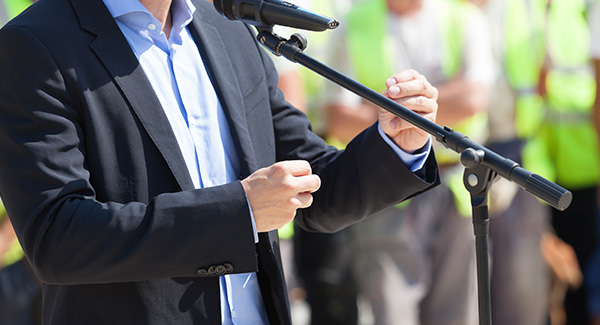 male speaker outside with audience