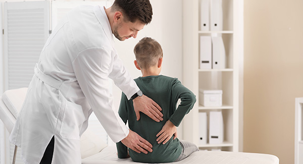 Médico revisando la espalda de un niño