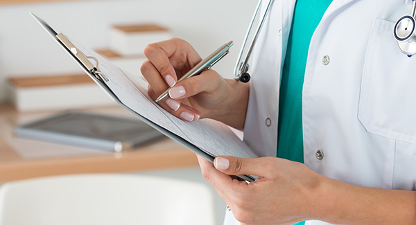 physician writing on a clipboard