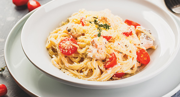 Tallarines integrales cremosos con salmón, col rizada, tomates y queso de cabra