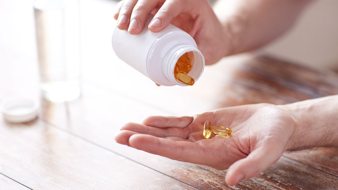 manos tomando suplementos de aceite de pescado