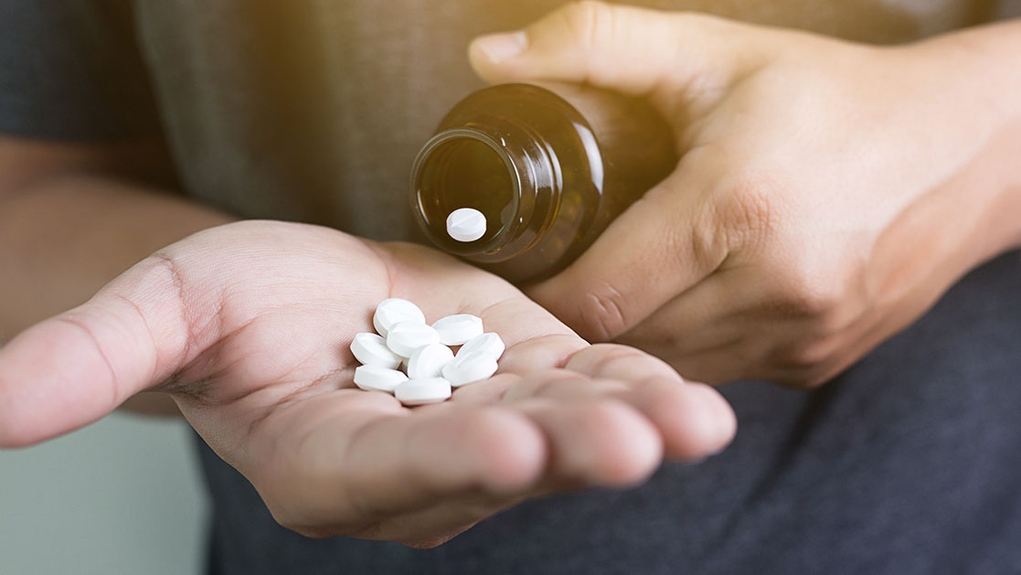 manos sacando pastillas de un frasco
